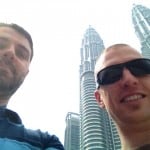 Luke and Matt smile with the Petronas Towers looming in the background
