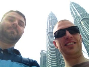 Luke and Matt smile with the Petronas Towers looming in the background