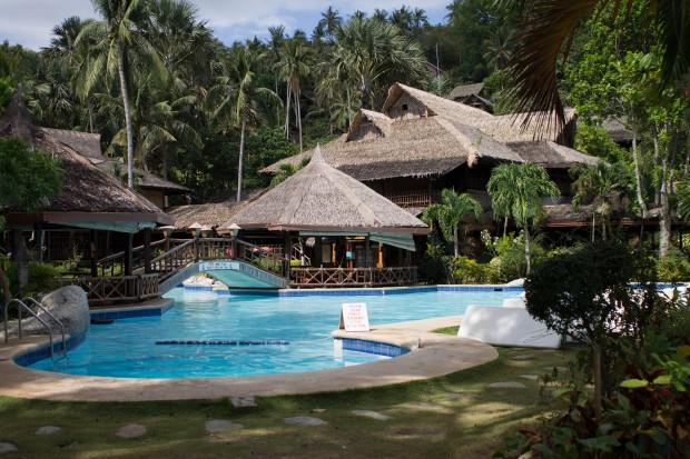 The pool at Coco Beach, with some thatched huts beyond