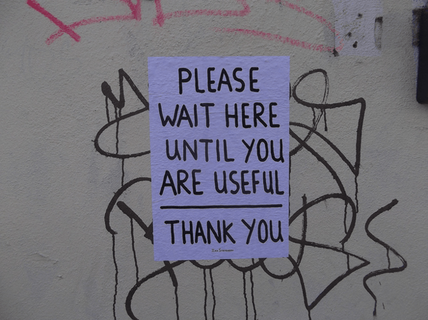 Sign saying "Wait here until you are useful."
